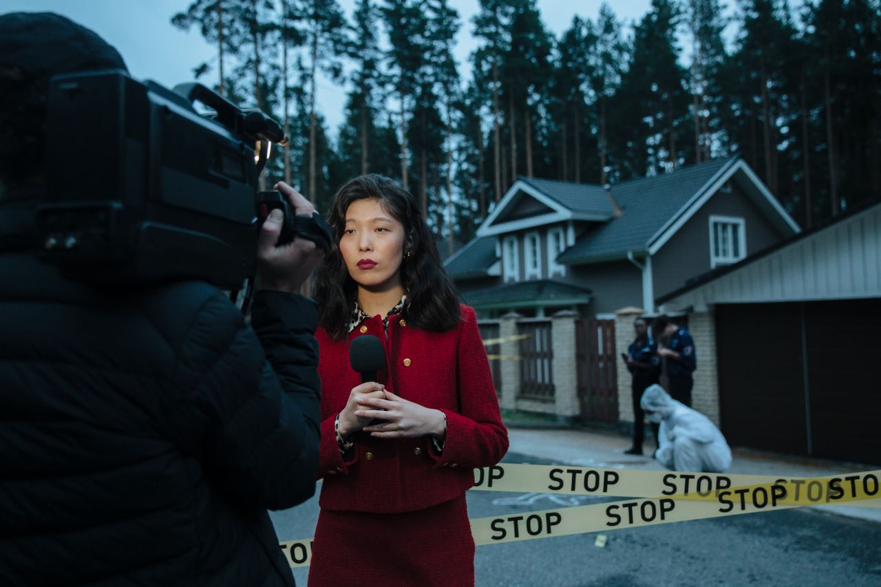 Services Female journalist reporting live from a crime scene with police and cameraman.